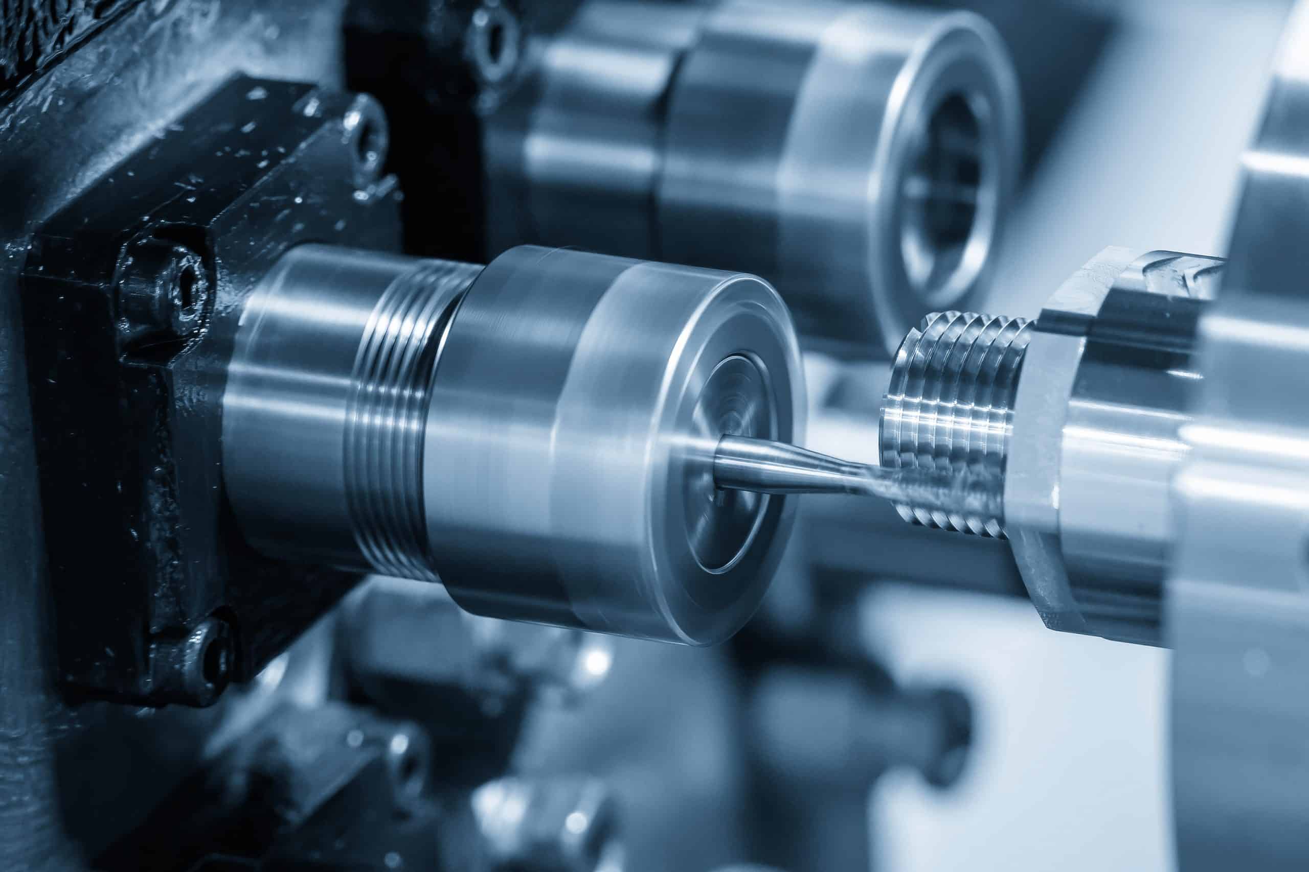 Close-up of a tap threading a metal part on a CNC lathe.